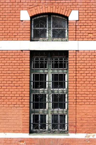 地元の駅の赤レンガの壁にマウント保護錬鉄バーや装飾フレームと長い細長い古い窓 — ストック写真