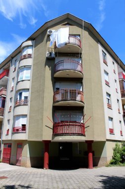 Yenilenmiş eski apartmanın köşesi. Çok sayıda yuvarlak balkonları metal çitlerle çevrili ve temiz mavi arka planda taş fayanslarla çevrili.