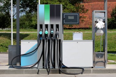 Dört farklı yakıt çeşidine sahip modern benzin istasyonu pompası ve metal tutucunun yanında yerel benzin istasyonunda kağıt havlu ve çöp tenekesi ile şeffaf tek kullanımlık plastik eldivenler için dijital ekran