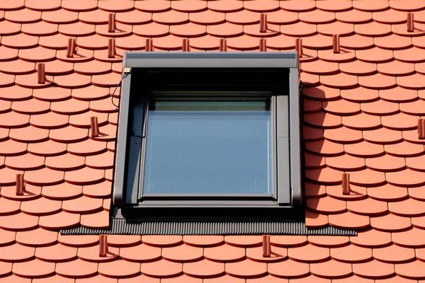 Yeni inşa edilen banliyö aile evinin tepesine yeni çatı kiremitleri ve kar koruyucularıyla çevrili güçlü metal çerçeveli modern yeni dikdörtgen çatı penceresi.
