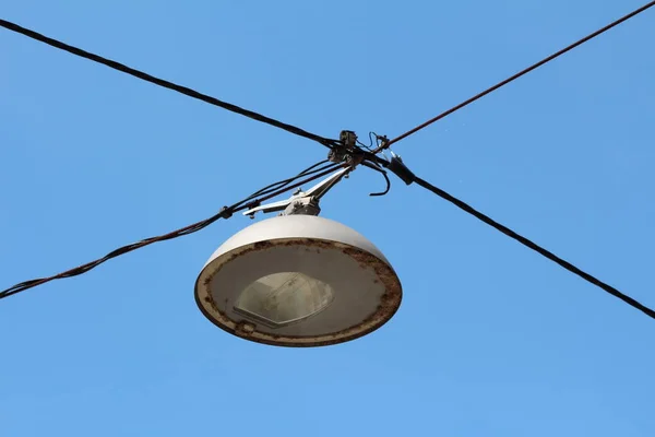 旧式复古风格的大型圆形路灯 装有坚固的金属外壳 在街道交叉口上方悬挂深色电线 蓝天背景清晰 — 图库照片