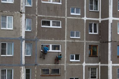 Tırmanışçılar yüksek binadaki pencereleri onarıyor.