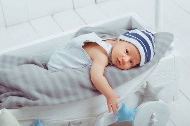 innocent little infant baby lying in wooden baby cot clipart