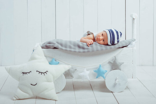 innocent little infant baby lying in wooden baby cot