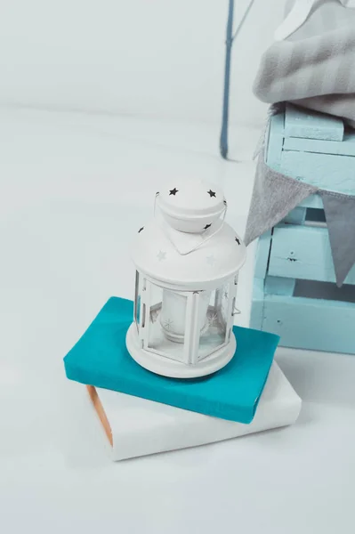 close up view of white lantern on books near blue wooden box