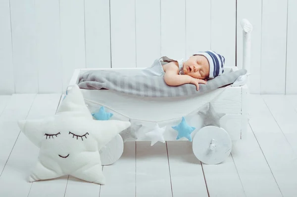 Retrato de bebé adorable en sombrero durmiendo en una cuna de madera decorada con estrellas — Stock Photo