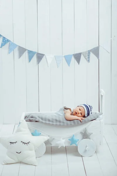 Adorable infant baby in hat resting in wooden baby crib decorated with stars — Stock Photo