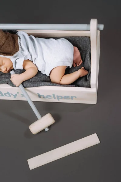 Partial view of adorable baby with hammer in hand sleeping in wooden toolbox with daddys helper lettering — Stock Photo