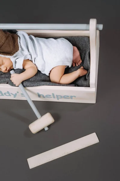 Vue partielle de bébé adorable avec marteau à la main dormant dans une boîte à outils en bois avec lettrage daddys helper — Photo de stock