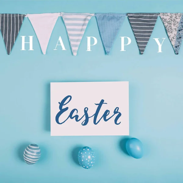 Top view of greeting card with happy easter lettering and easter eggs on blue surface — Stock Photo