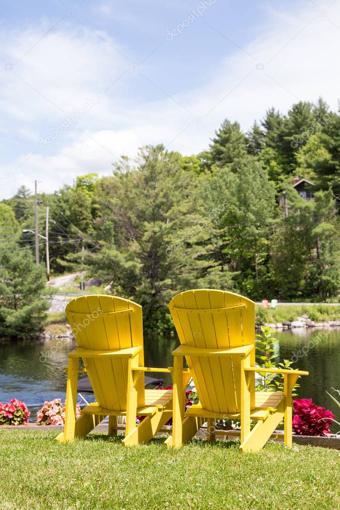 vertical pair of yellow muskoka chairs at lake