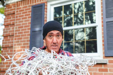 horizontal of a man with tangled Christmas lights clipart