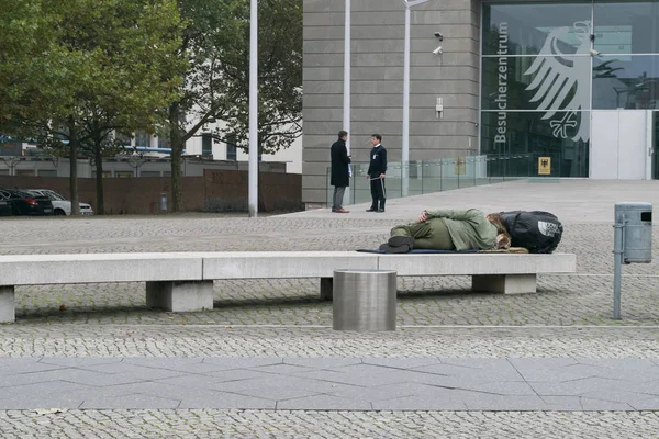 BERLÍN - 18 DE OCTUBRE DE 2016: Un hombre duerme en un banco frente a un edificio gubernamental en Berlín . —  Fotos de Stock