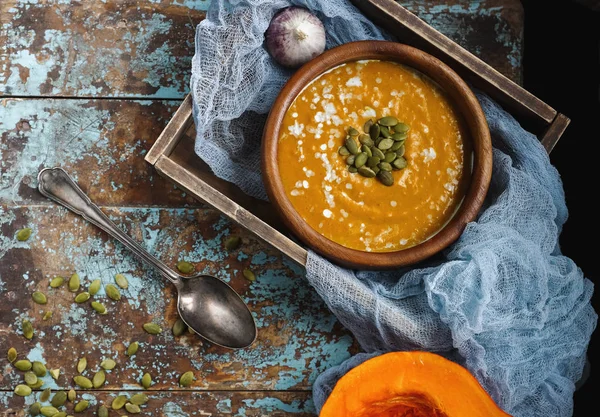 Bowl of traditional homemade pumpkin soup with seads, cream and bread on rustic wooden table — Stock Photo, Image