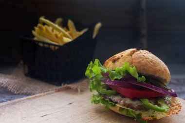 Ev yapımı hamburger taze domates, marul, soğan ve patates kızartması rustik ahşap tahta üzerinde. Fast food, sağlıksız yeme
