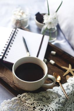 Şekerleme, çikolata, çiçek ve smartphone rahat yatakta rustik ahşap tepsi üzerinde ev yapımı kakao fincan