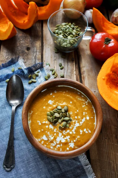 Traditional homemade pumpkin soup with seads, cream and vegetables on rustic wooden table — Stock Photo, Image