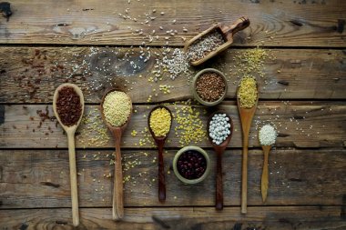 Ham organik tahıl tahıllar, tohum ve fasulye rustik ahşap zemin üzerine tahta kaşıklar