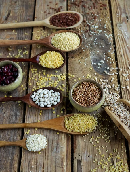 Raw organic cereal grains, seeds and beans in wooden spoons on rustic wooden background — Stock Image Raw organic cereal grains, seeds and beans in wooden spoons on rustic wooden background Stock Image