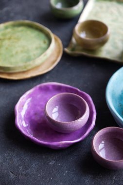 Ev yapımı rustik çanak çömlek, renkli tabaklar ve karanlık taş beton zemin üzerine kase