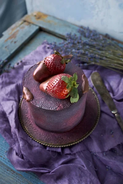 Beautiful purple cake decorated with chocolate and strawberries