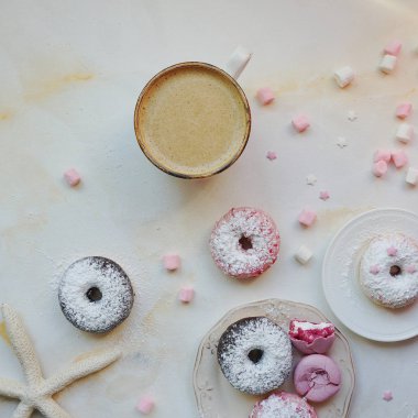 Çilekli ve lavantalı makarna, bir fincan kapuçinolu tatlı çörek ve beyaz mermer masada marşmelov, tatlı ve kahve ile nefis kahvaltı.