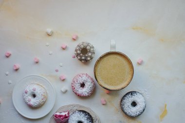 Çilekli ve lavantalı makarna, bir fincan kapuçinolu tatlı çörek ve beyaz mermer masada marşmelov, tatlı ve kahve ile nefis kahvaltı.