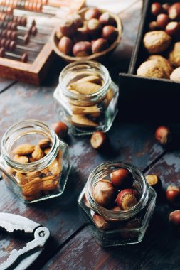Kutularda fındık, kase ve cam kavanozlar koyu ahşap masa, ceviz, badem, fındık, fındık, kaju, sağlıklı çeşitli süper yiyecekler, seçici odaklı