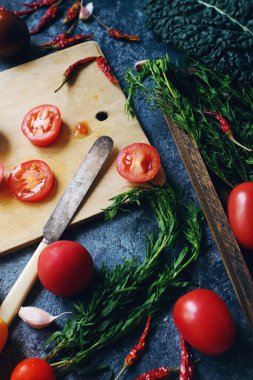 Koyu taş masa ve eski ahşap tahta, sağlıklı yaşam tarzı, organik gıda konsepti ve seçici odaklanma üzerine renkli çiğ domates ve otların karışımı.