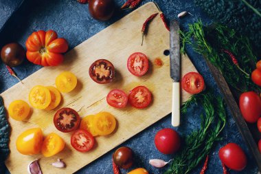 Renkli çiğ domates ve otların karışımı koyu taş masa ve eski tahta tahta tahta, sağlıklı yaşam tarzı, organik gıda konsepti, üst görünüm, seçici odaklanma.