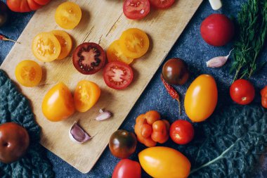 Renkli çiğ domates ve otların karışımı koyu taş masa ve eski tahta tahta tahta, sağlıklı yaşam tarzı, organik gıda konsepti, üst görünüm
