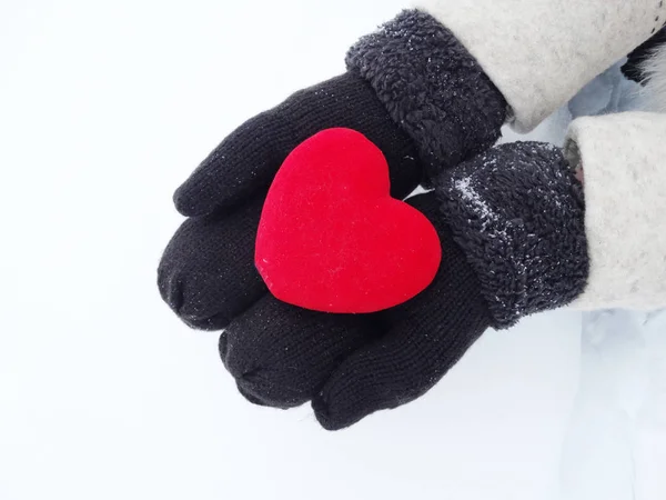 女人的手在手套与红色的心，在雪上 — 图库照片