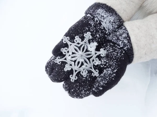 Manos de mujer en manoplas con decoración de copo de nieve en la nieve — Foto de Stock