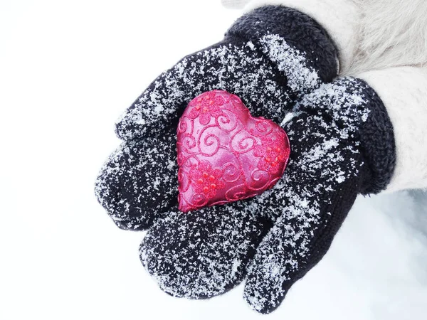 Manos de mujer en manoplas con corazón rojo en la nieve — Foto de Stock