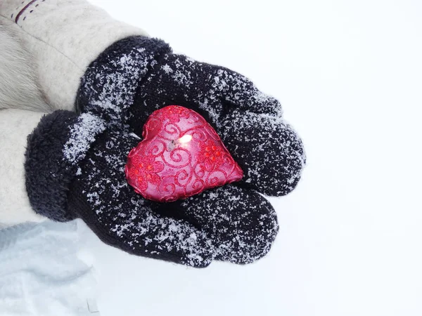 Руки женщины в рукавицах с красным сердцем на снегу — стоковое фото