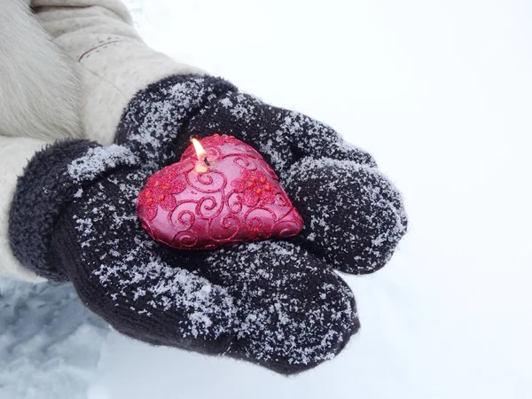 Manos de mujer en manoplas con corazón rojo en la nieve — Foto de Stock