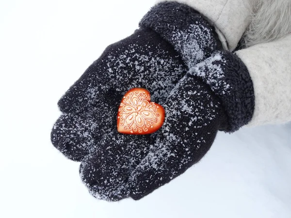 Manos de mujer en manoplas con corazón rojo en la nieve — Foto de Stock