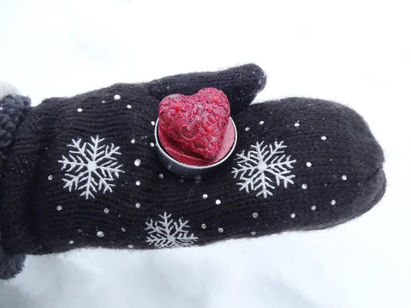 Руки женщины в рукавицах с красным сердцем на снегу — стоковое фото