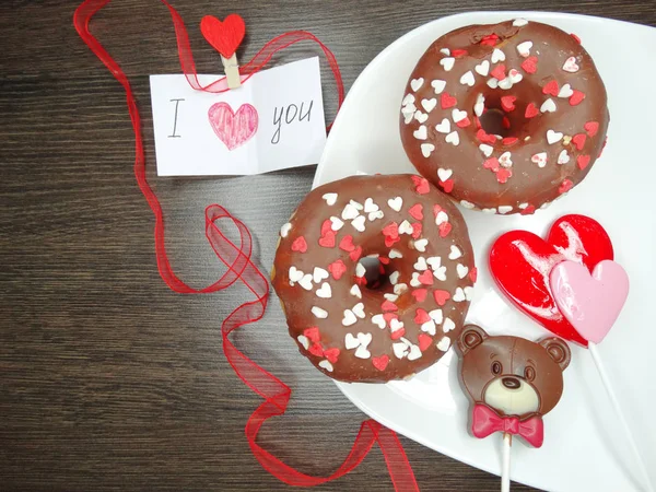 Día de San Valentín rosquillas de chocolate osito de peluche y tarjeta de felicitación —  Fotos de Stock