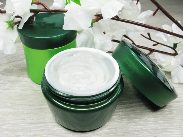 Creme cosmético para cuidados com o rosto e flores sakura brancas — Fotografia de Stock
