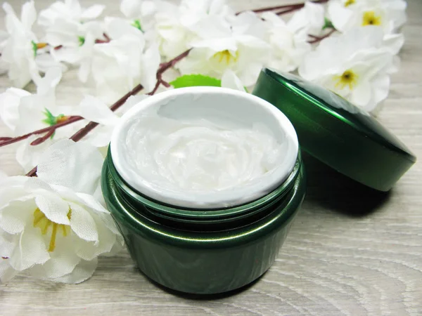 Crema cosmética para el cuidado de la cara y flores de sakura blancas —  Fotos de Stock