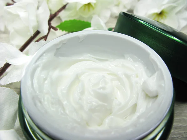 Crema cosmética para el cuidado de la cara y flores de sakura blancas — Foto de Stock