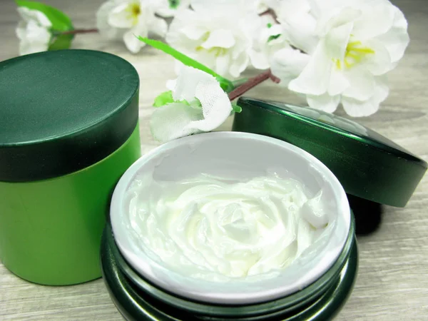 Cosmetische crème voor gezicht zorg en witte bloemen — Stockfoto