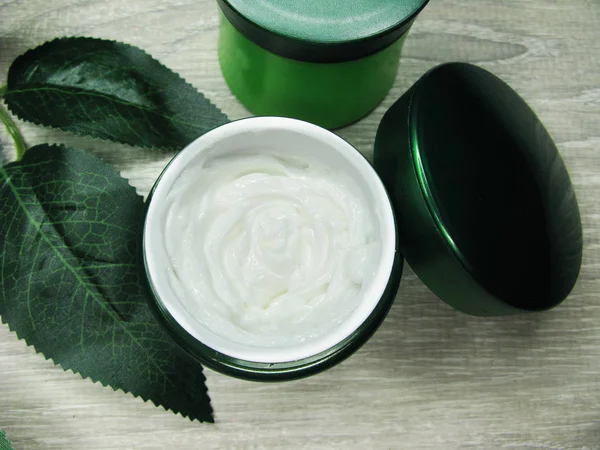 Creme cosmético para cuidados com o rosto e folhas verdes — Fotografia de Stock