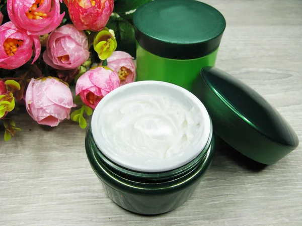 Cosmetische crème voor gezichts onderhoud en roze bloemen — Stockfoto