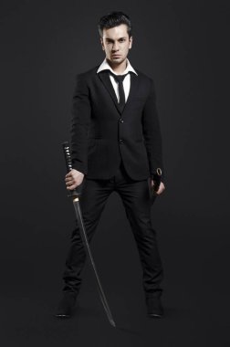 Siyah arka plan üzerine poz katana ile takım elbiseli adam 