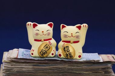 İki şanslı kedi (Maneki-Neko) banknotlar yığını üzerinde. Tablet 