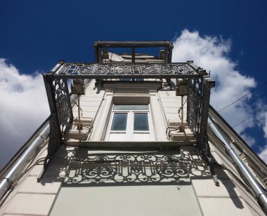 Corner facade of the building. Openwork cast-iron lattices of balconies without a floor. View from the bottom up. clipart