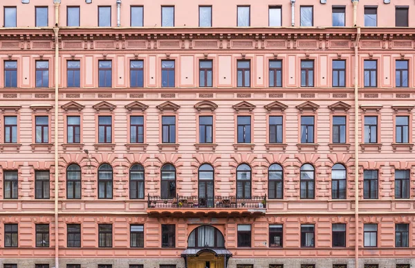 Coral colored classical facade of a multistorey old building with a built-up floor.  Front view close up.