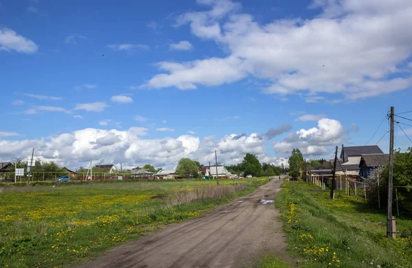 PERESLAVL-ZALESSKY, RUSSIA,- typical view of small historic town in Russian province: space, sky, rural street, lawns, wooden houses, electric poles, gas pipeline, dirt road, puddles